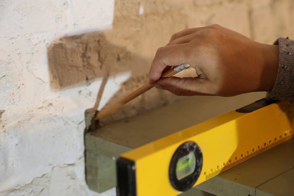 Illustrative photo: marking a wall with a spirit level before a repair