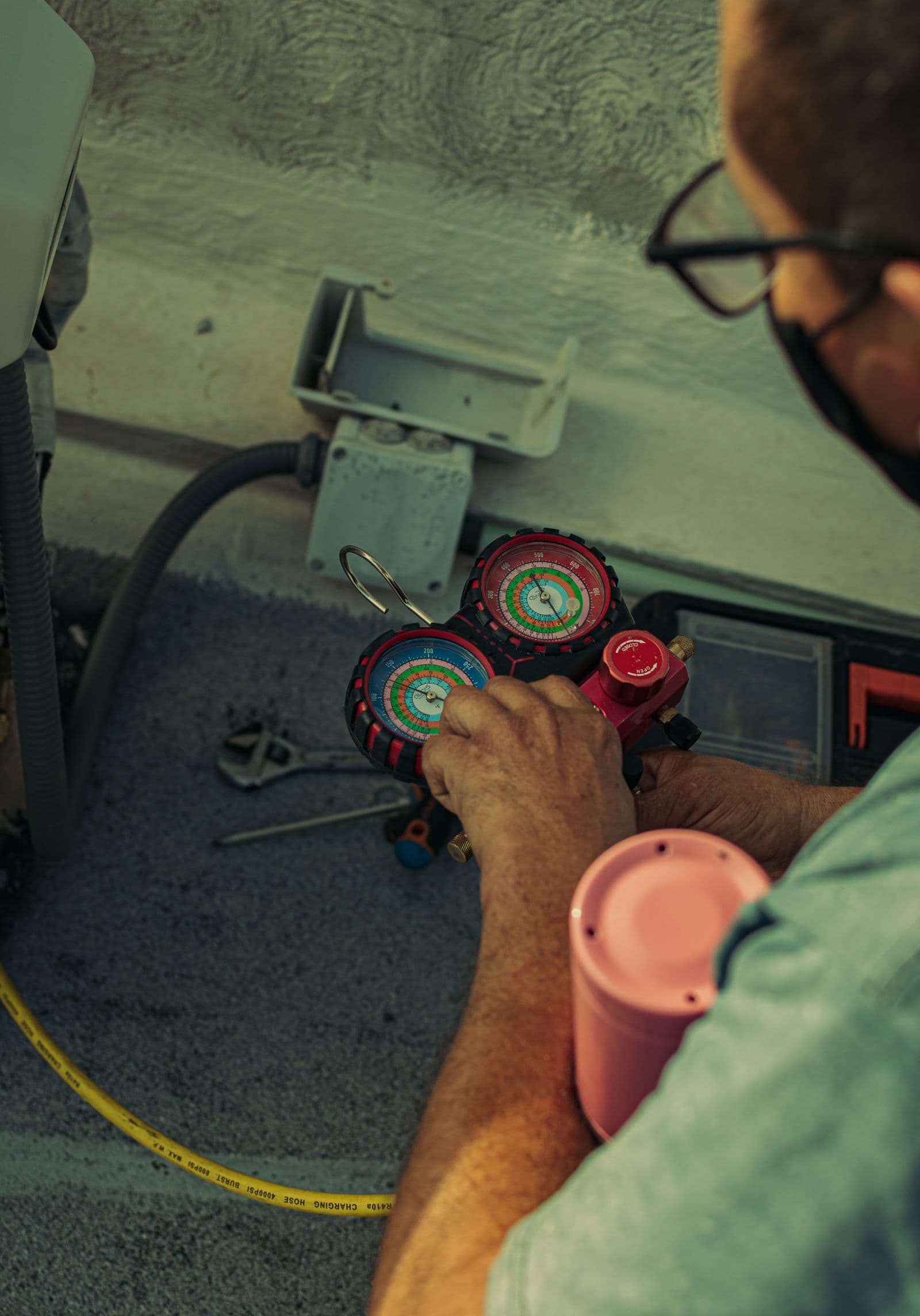 Technician checking an AC unit's pressure gauges during a service