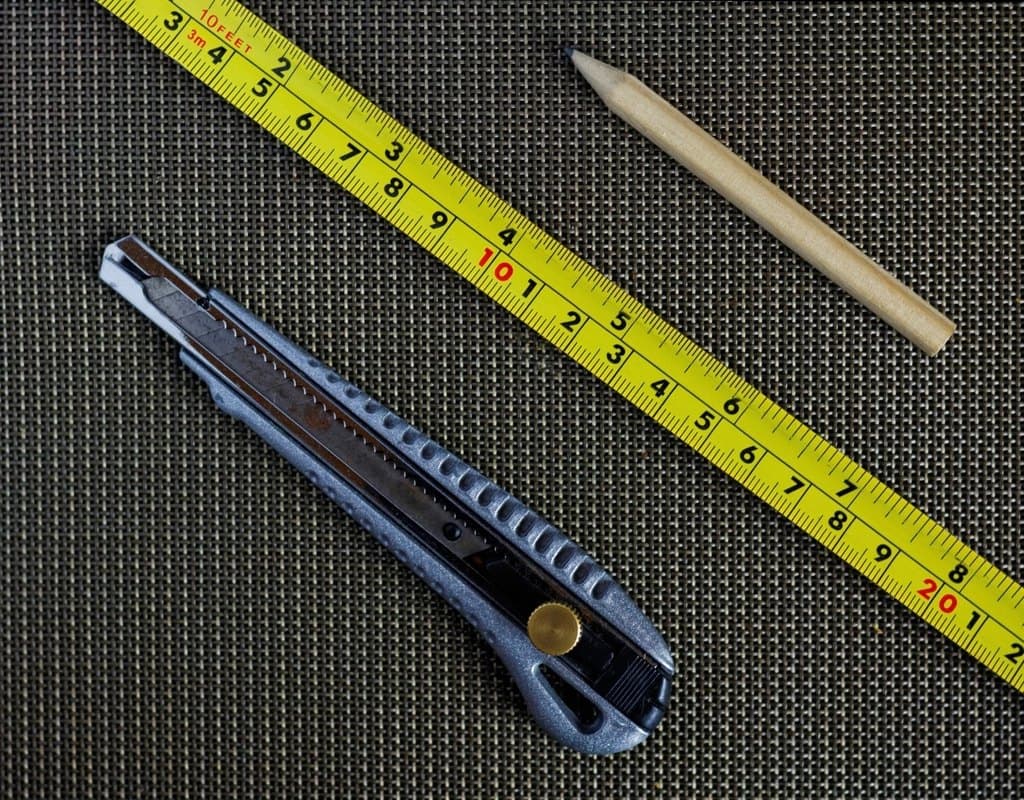 Measuring tape, utility knife and pencil laid out before a job