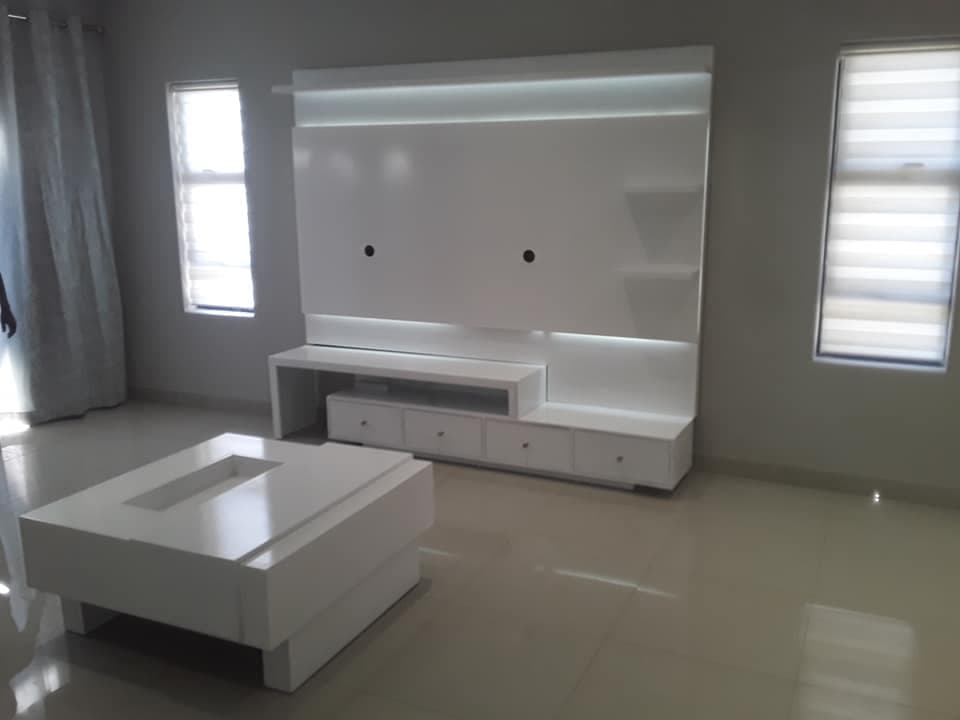 Built-in white media wall with TV recess, LED strip lighting, shelves and low cabinets