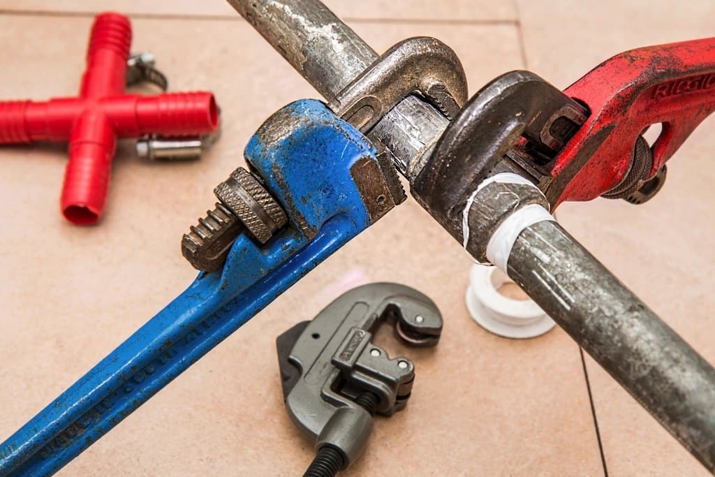Pipe wrenches and plumbing tools on a tiled floor